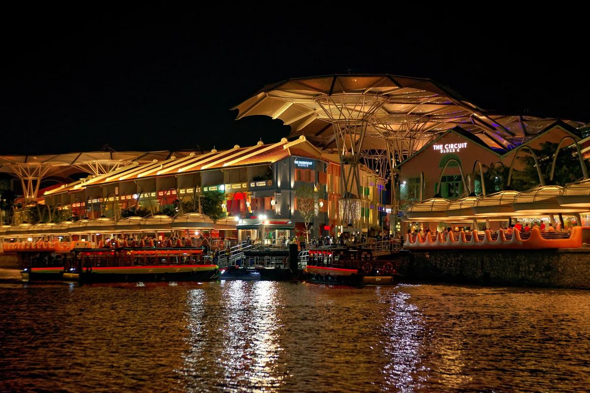 Clarke Quay's canopies and bars reflected in the river at night, Singapore