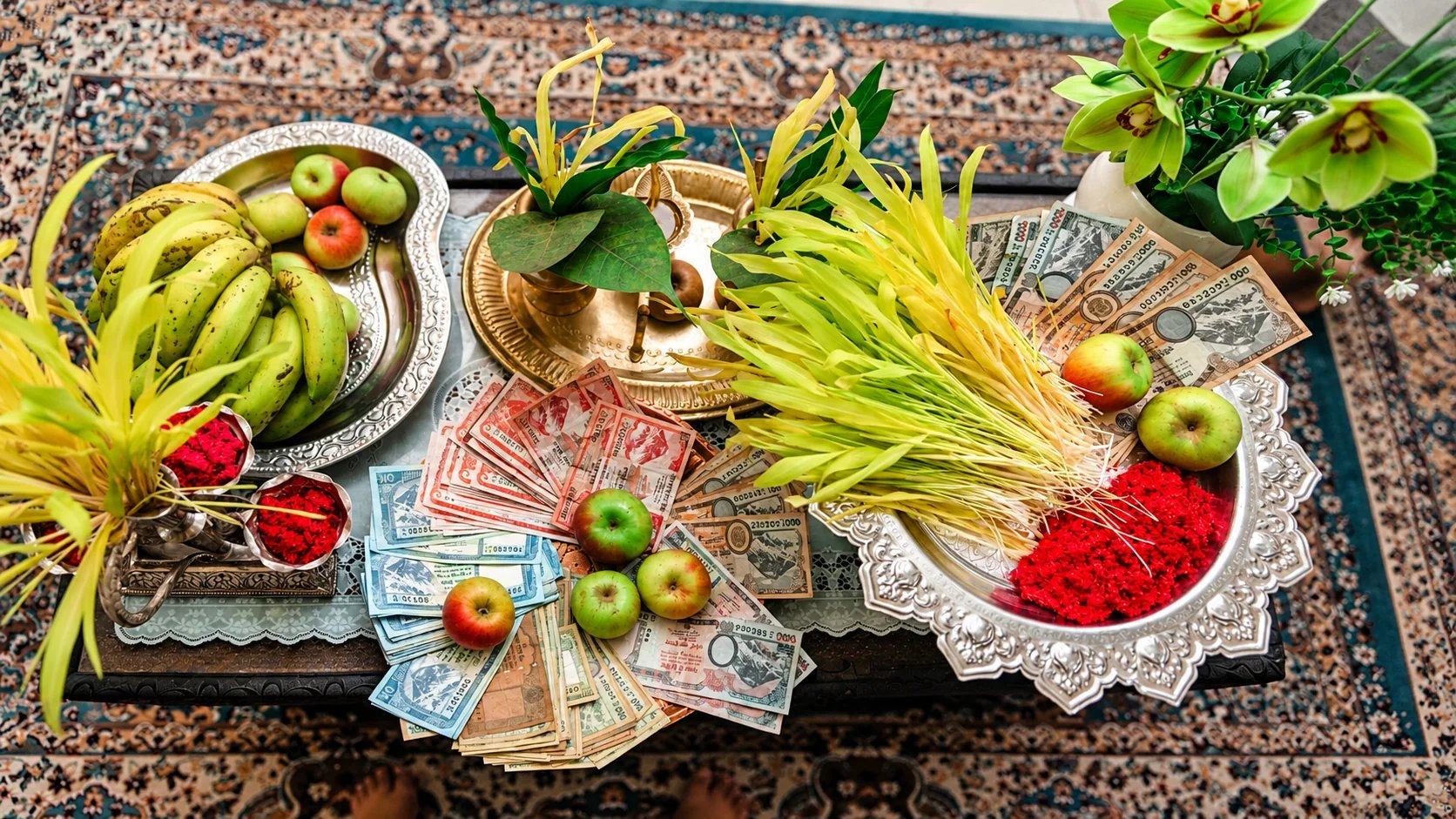 A Dashain tika table with jamara shoots, red tika, fruit and banknotes for dakshina, Nepal