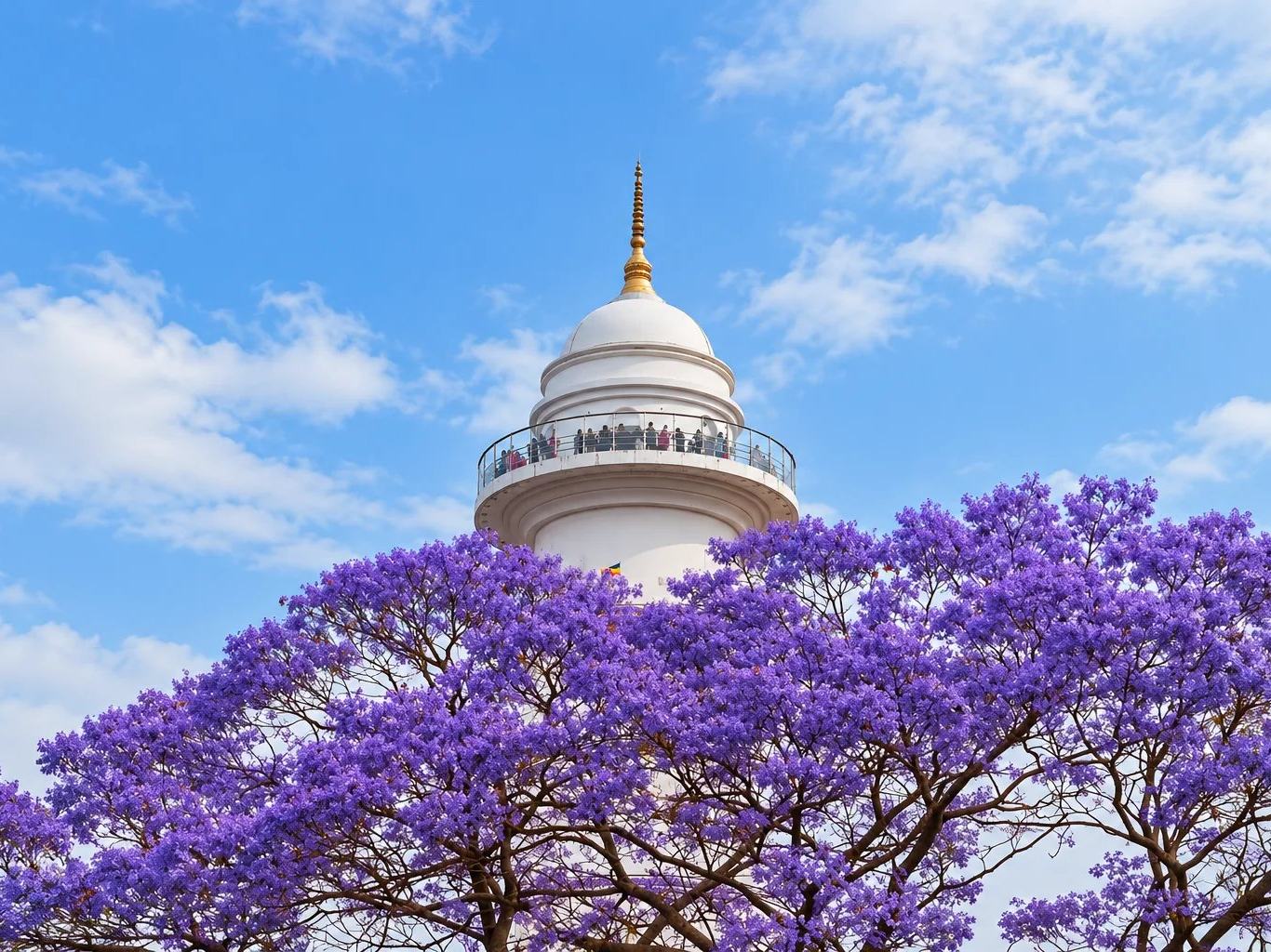 Purple jacaranda blossom below the white Dharahara tower and its viewing gallery, Kathmandu, Nepal