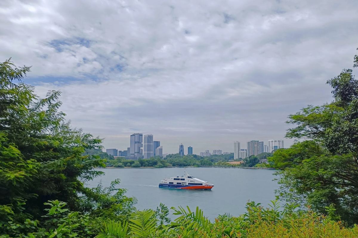 A ferry crossing the strait below Fort Siloso, seen through the trees, Singapore