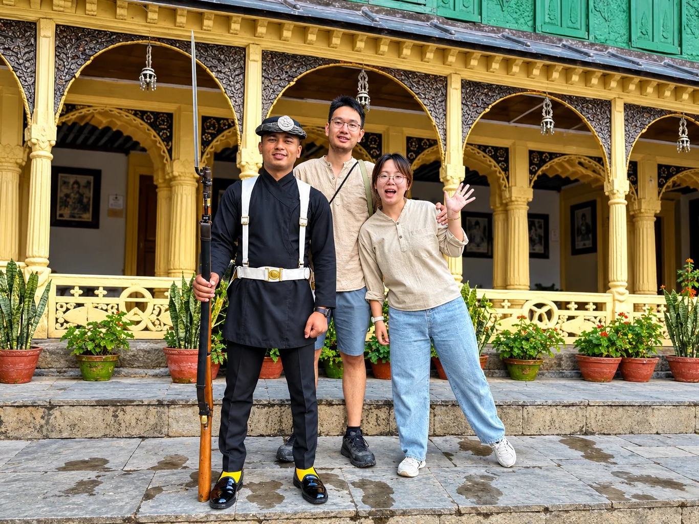 Travellers with a uniformed guard at the ornate porch of a heritage palace building in Kathmandu, Nepal