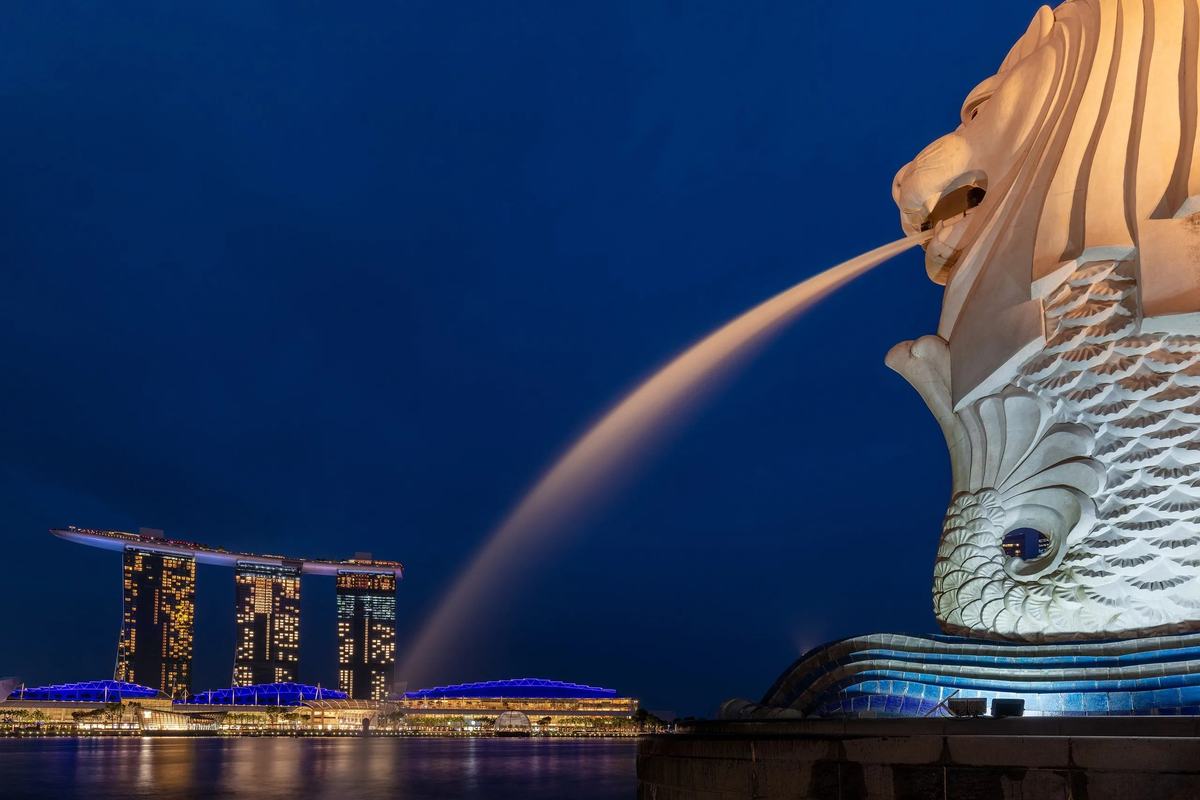 The Merlion spouting water at night, with Marina Bay Sands across the bay, Singapore