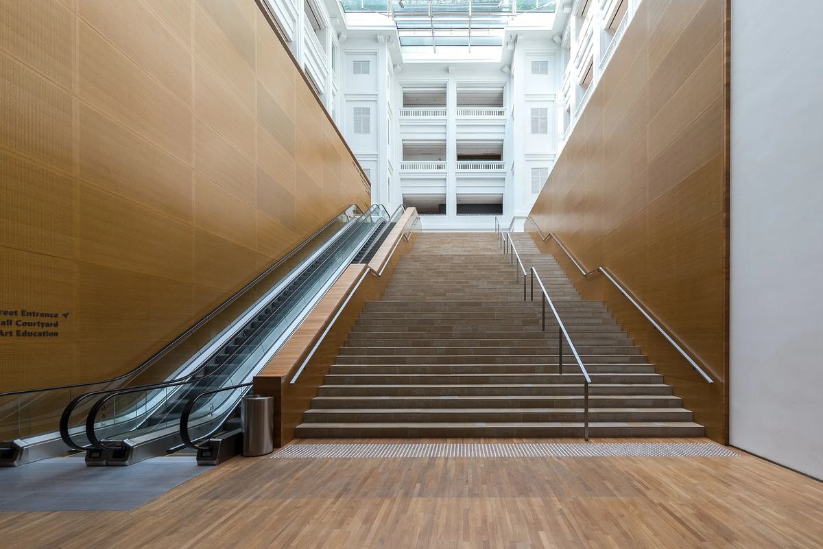 Stairs and escalators rising to a glass-roofed hall in the National Gallery, Singapore