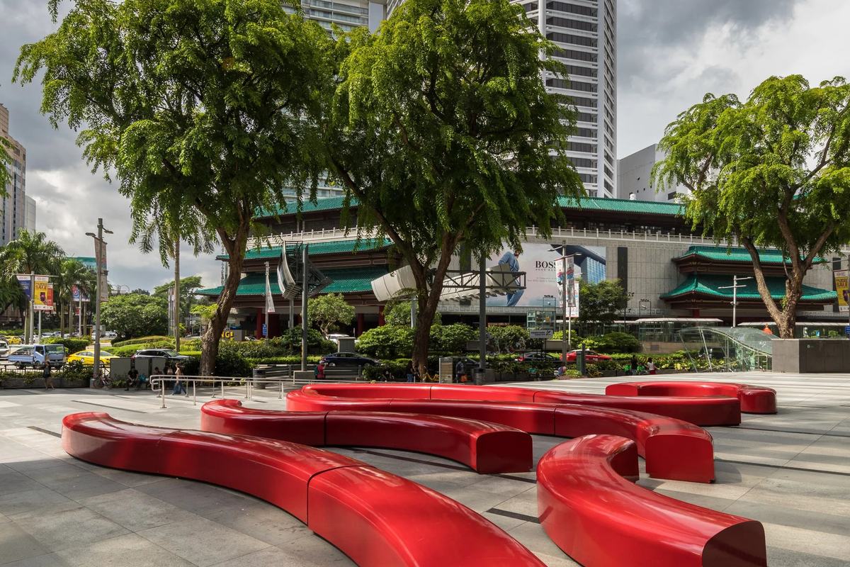 Red sculptural benches on an Orchard Road plaza below a pagoda-roofed tower, Singapore