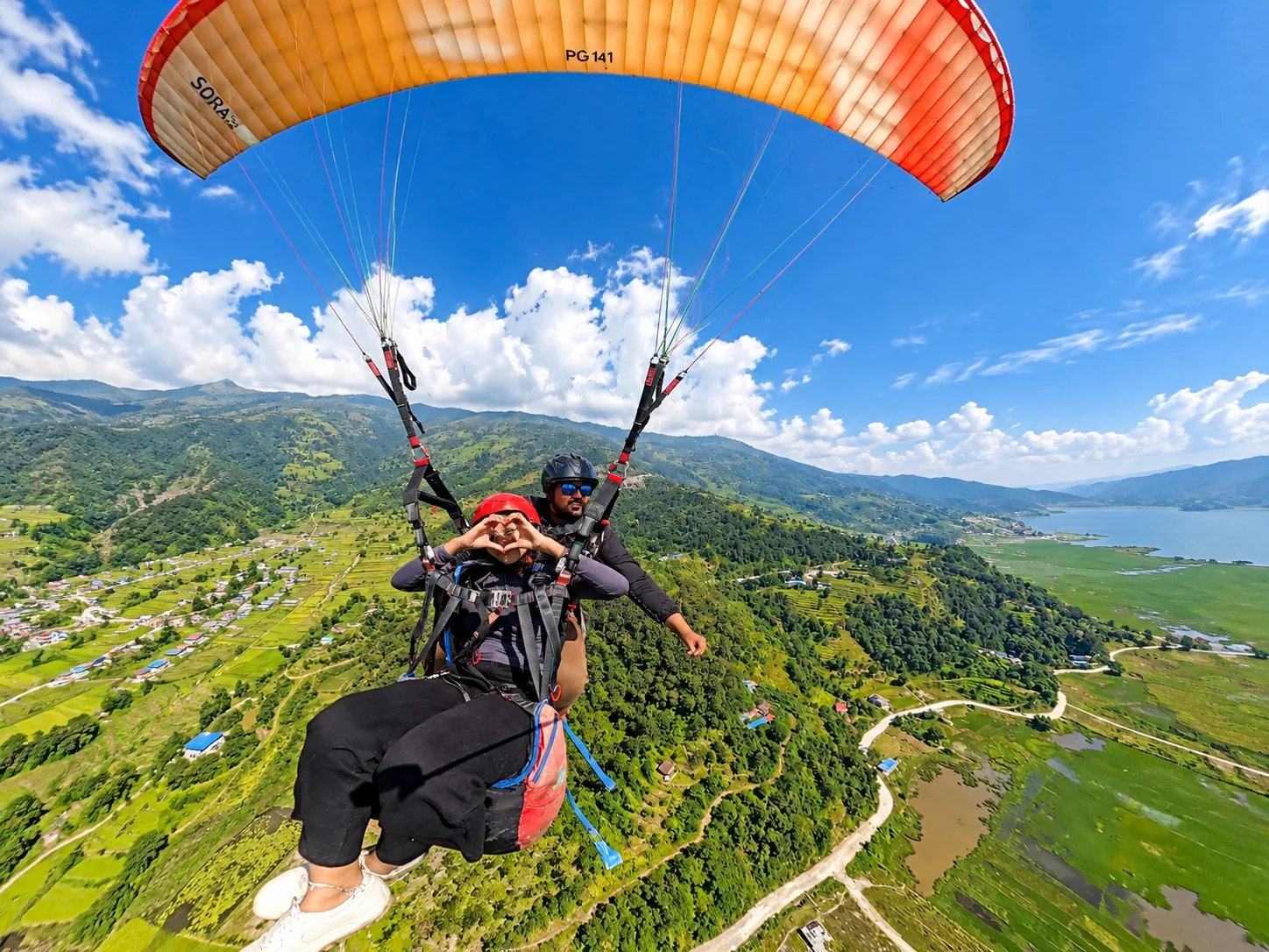 A tandem paraglider above terraced valleys and Phewa Lake, Pokhara, Nepal