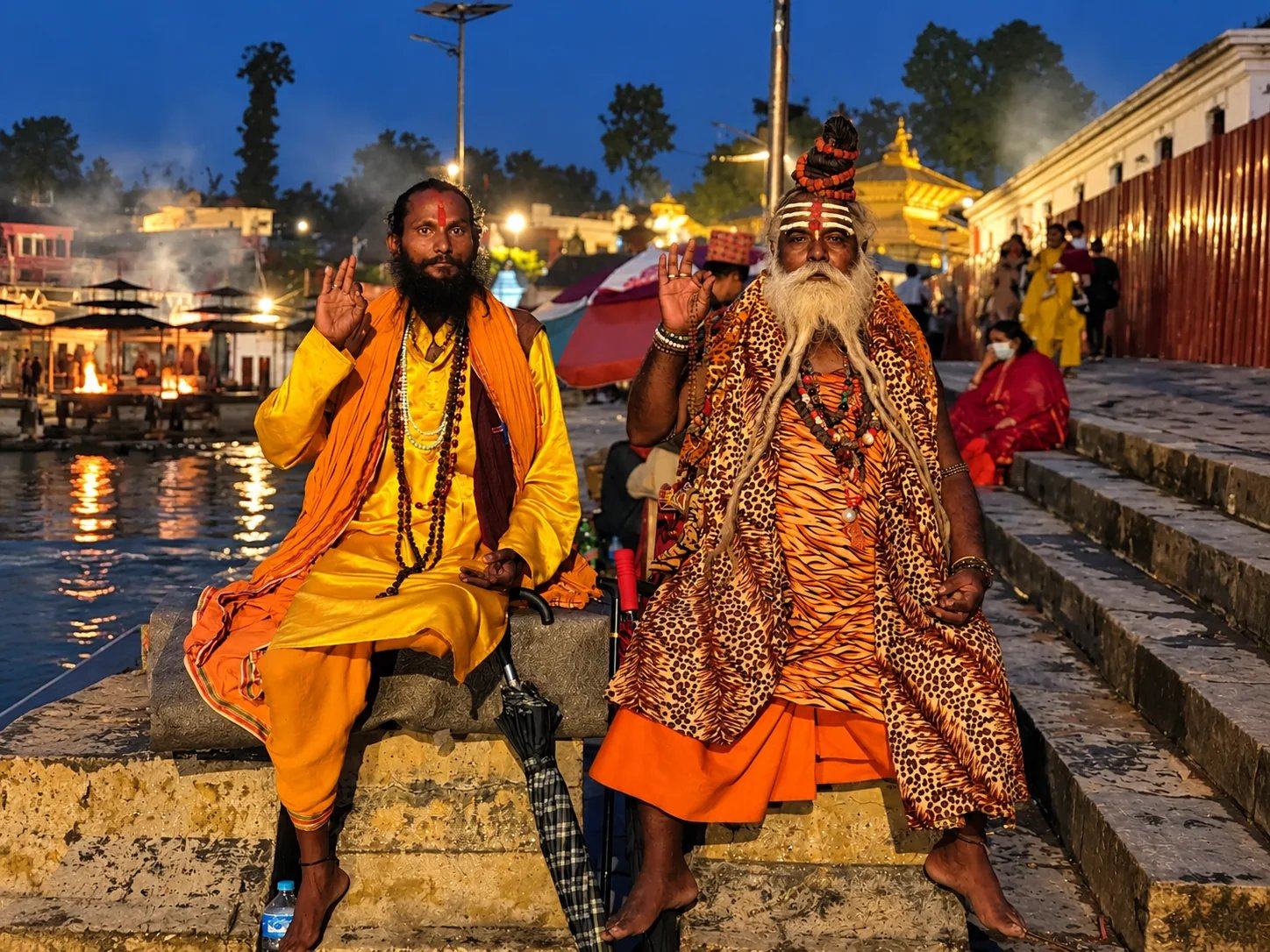 Two sadhus in saffron robes on the evening ghats of the Bagmati River at Pashupatinath Temple, Kathmandu