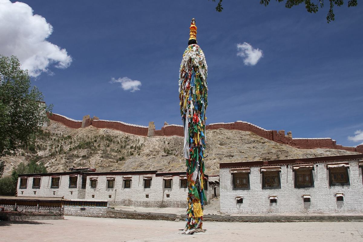 The courtyard of Pelkor Chode Monastery with its prayer pole and the town wall behind, Gyantse, Tibet