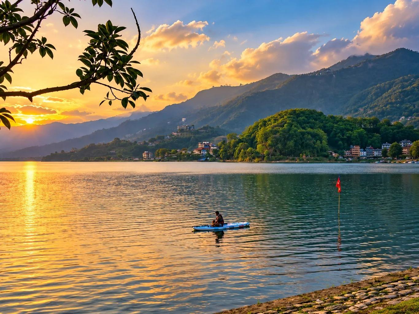 A kayaker on Phewa Lake at sunset below the forested hills of Pokhara, Nepal