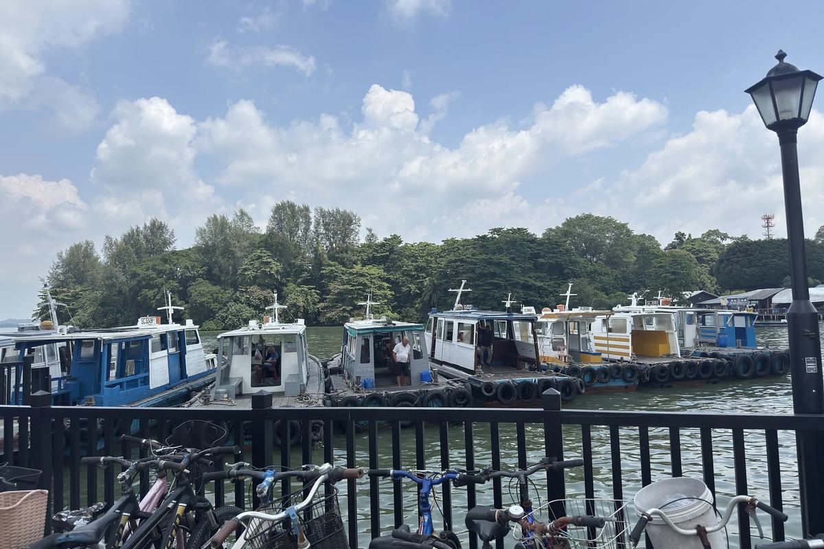 Bumboats moored at the Pulau Ubin jetty, with bicycles along the railing, Singapore