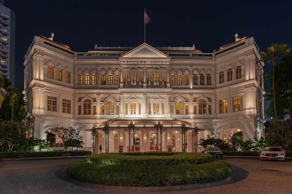 The white facade of Raffles Hotel lit up at night, Singapore