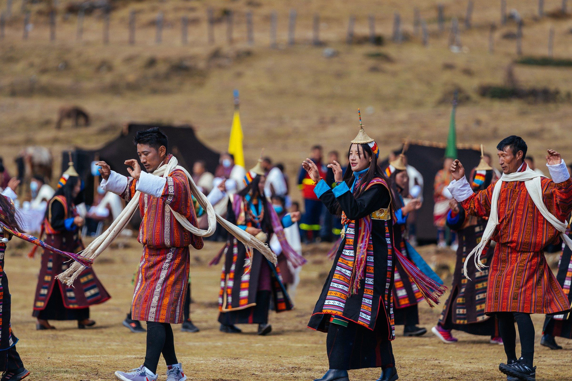 Highland dancers with white scarves, a Layap woman in her conical hat among them, before the yak-hair tents.