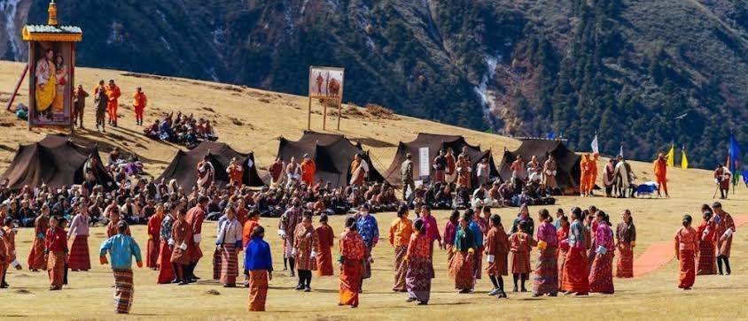 The festival ground at Laya: dancers on the meadow, black yak-hair tents and spectators on the slope above.
