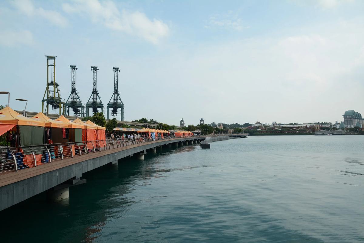The Sentosa Boardwalk over the water, with port cranes on the mainland, Singapore