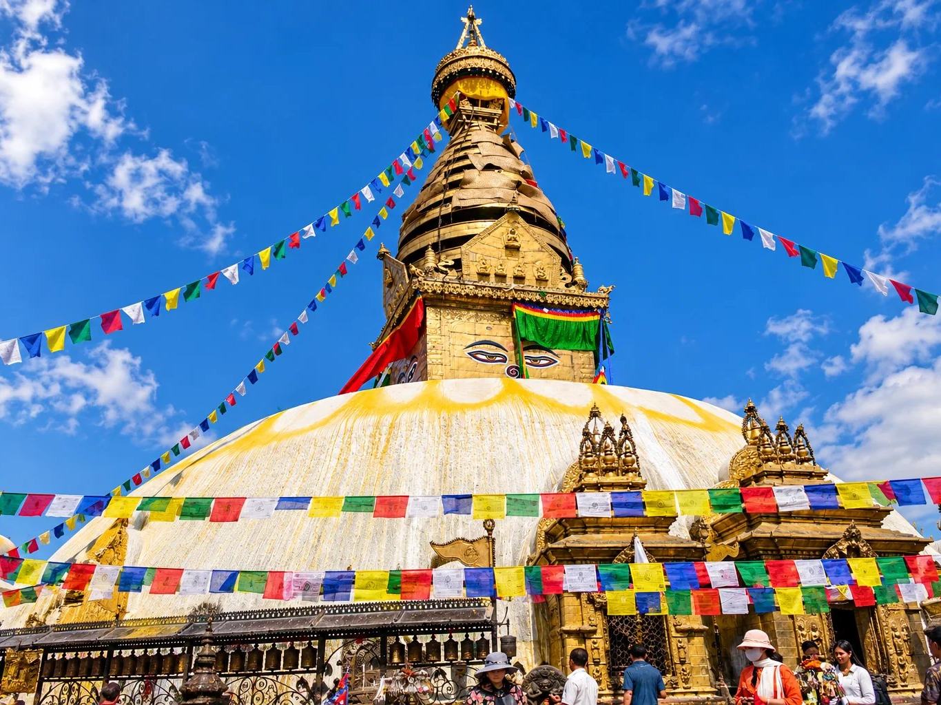The golden spire and painted eyes of Swayambhunath Stupa under prayer flags, Kathmandu, Nepal