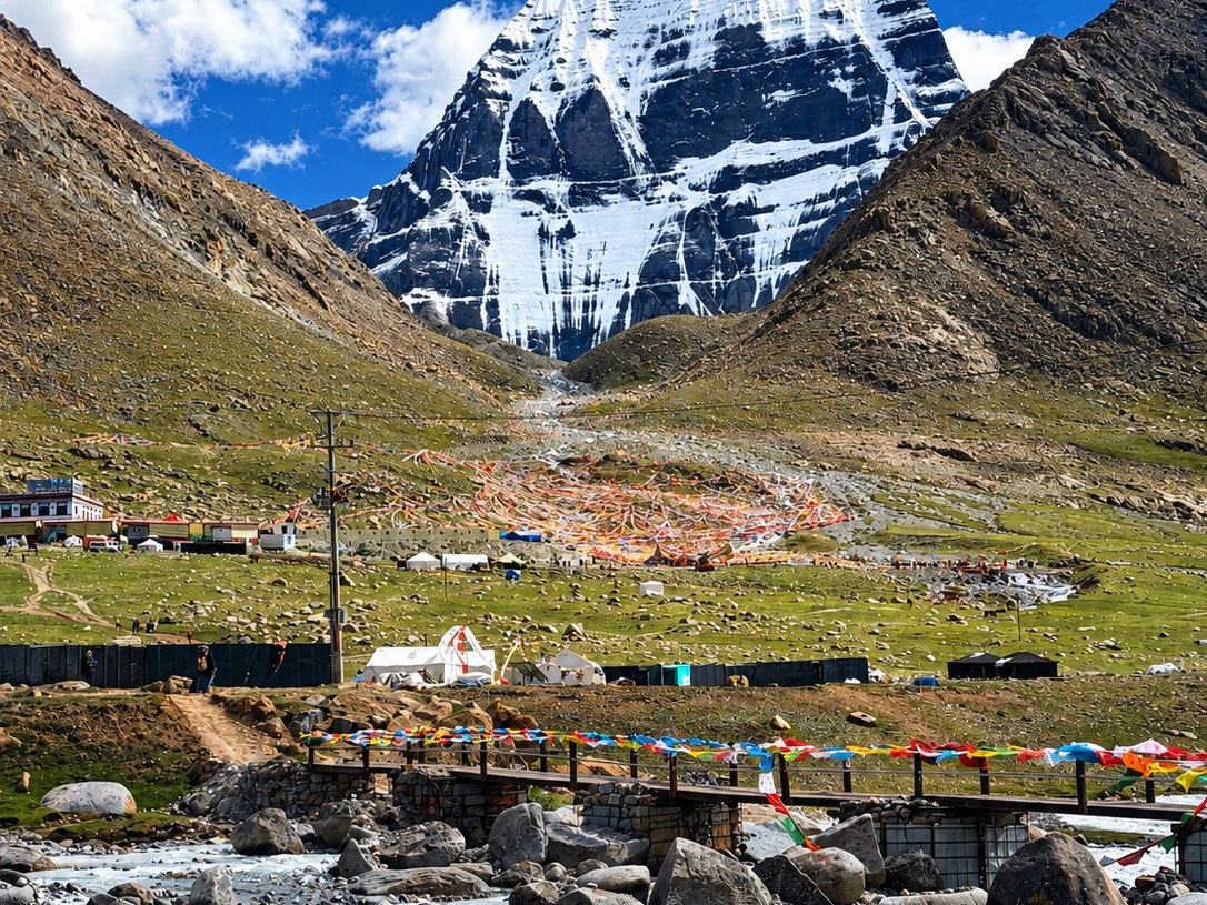 The north face of Mount Kailash above the pilgrim camp at Darchen, prayer flags strung over the meltwater river in the foreground
