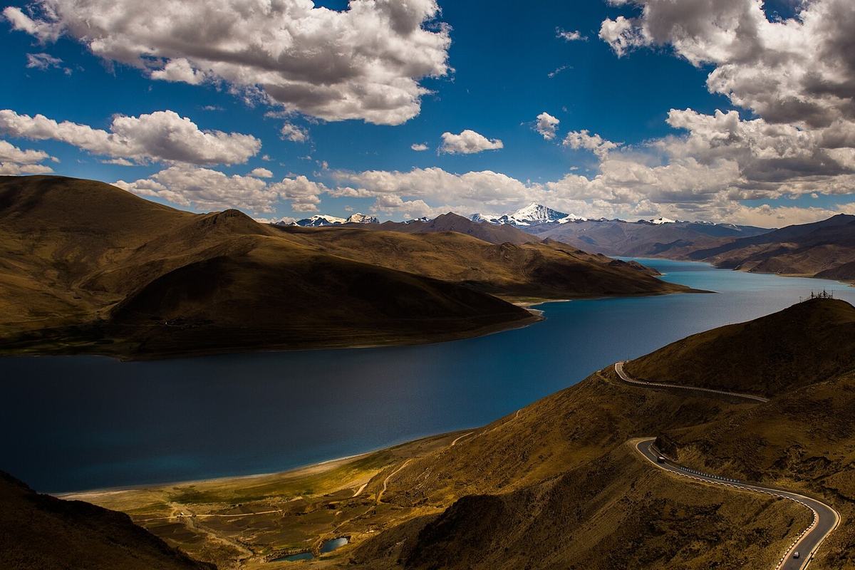Yamdrok Lake winding between brown hills below the road over the pass, Tibet