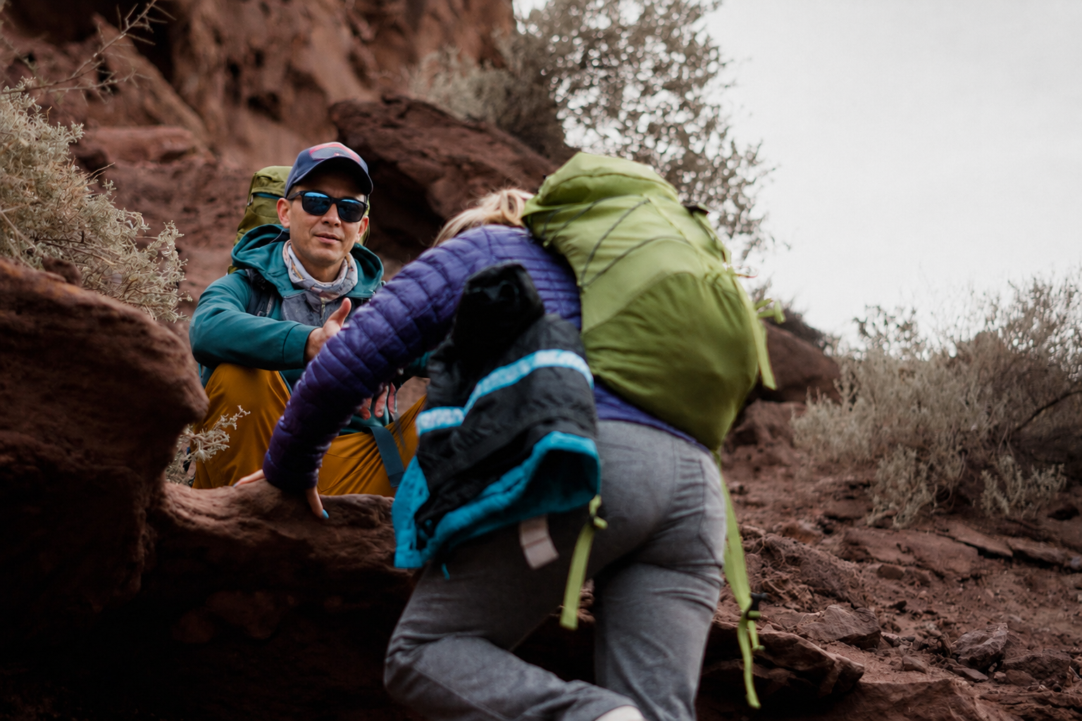 A private guide giving a trekker a hand up a rocky trail