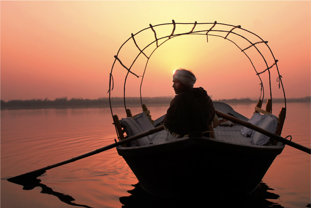 A man paddling a canoe in the midst of the Ganges.