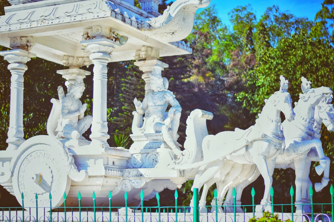A set of carved statues that represent a horse, reins, a chariot and charioteer with a master also seated in the chariot.