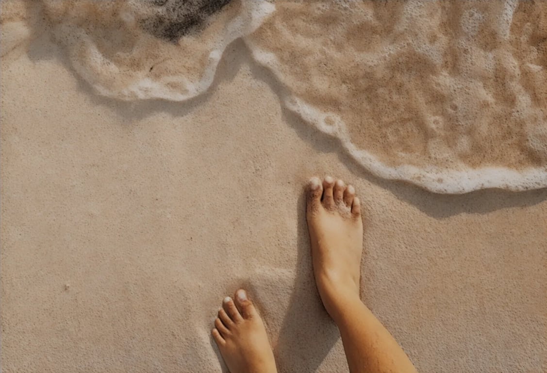 barefoot person standing on beach