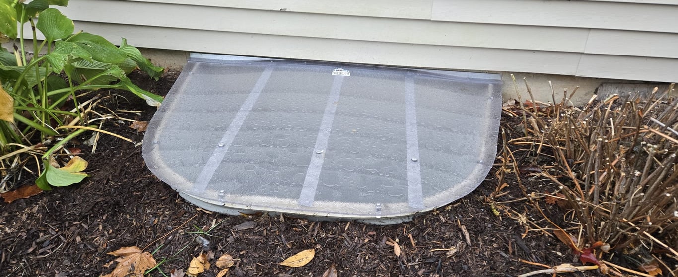 Frosted polycarbonate window well cover protecting basement windows year round in Naperville Illinois