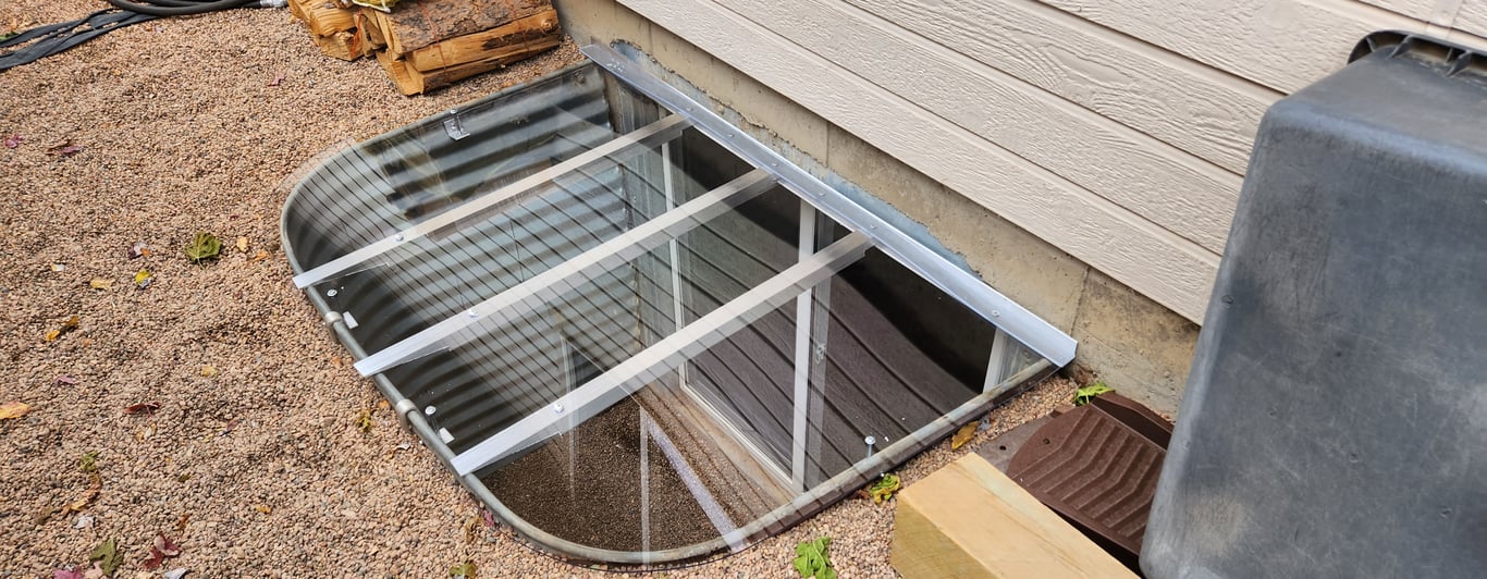 Clear polycarbonate window well cover installed near firewood in Arlington Heights Illinois