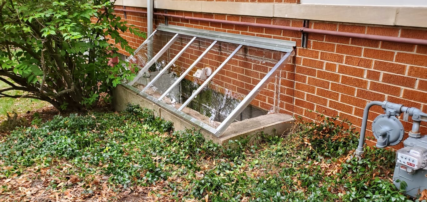 Slanted sloped clear polycarbonate window well cover installed in Parker Colorado for rain and snow shedding