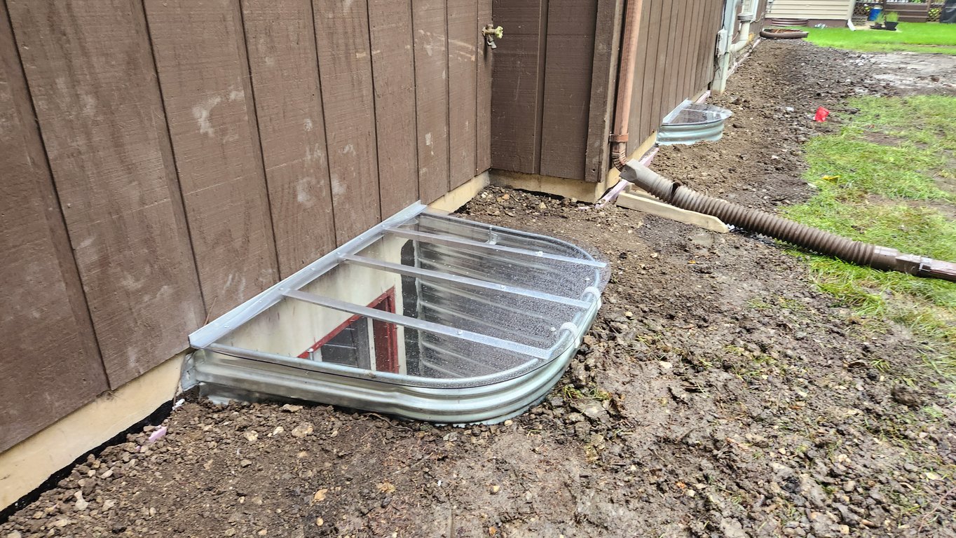 Installing clear polycarbonate window well covers during a rainy day in Broomfield Colorado