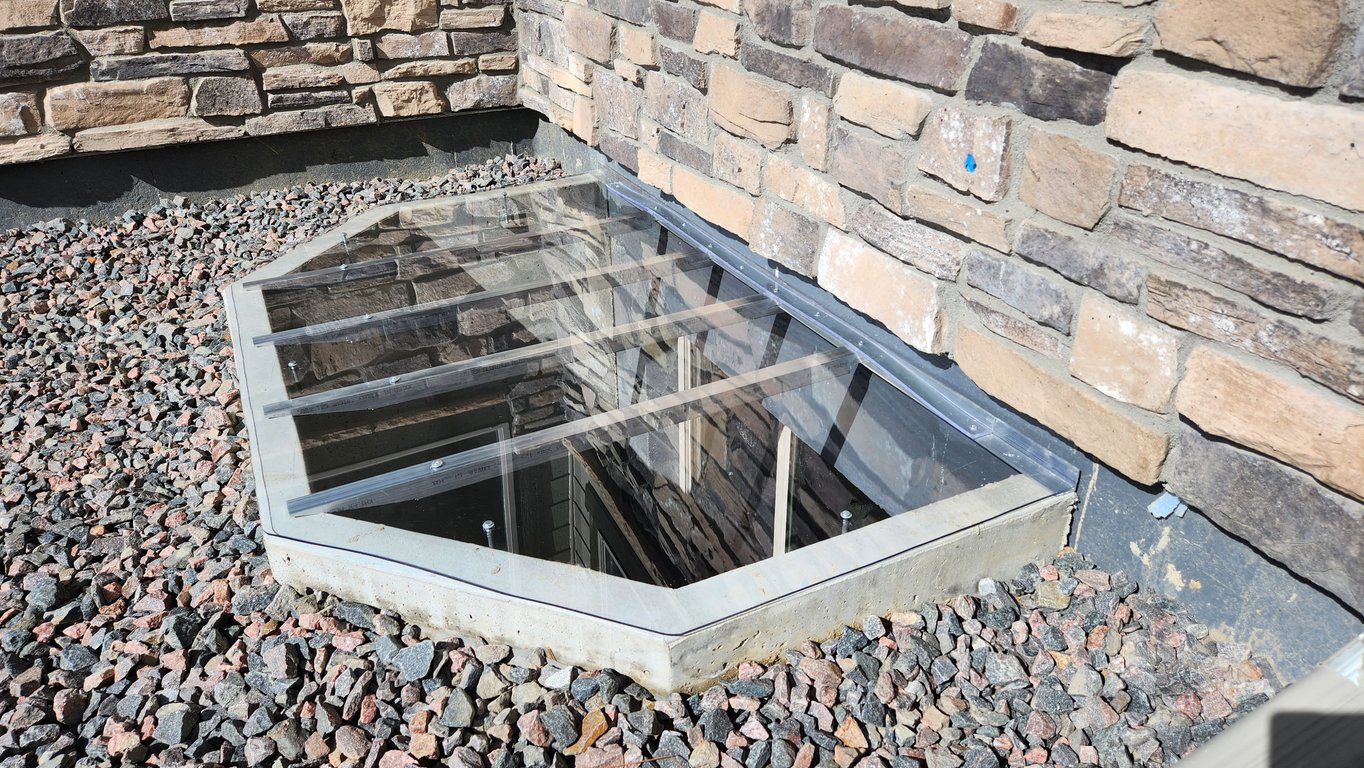 Clear custom window well cover installed in Mokena Illinois enhancing safety while maintaining full light entry