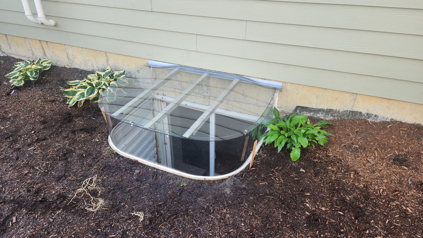 Polycarbonate extension riser with a sloped clear polycarbonate window well cover with clips installed in Erie Colorado