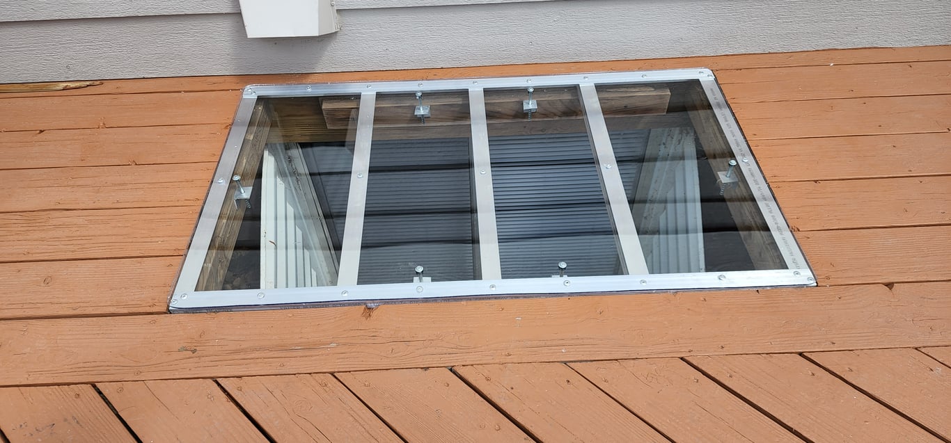 Square custom window well cover installed on a wood deck with locks in Downers Grove Illinois