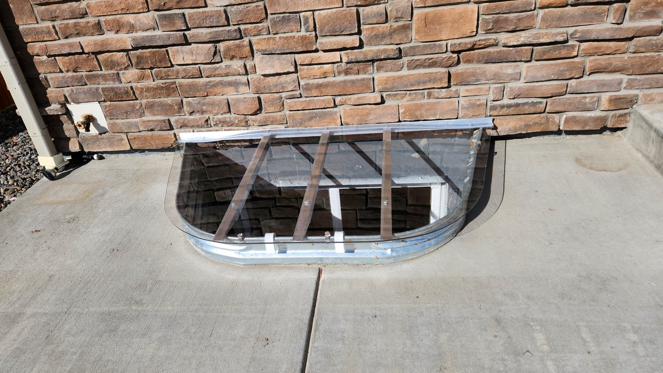 Window well replacement project in Parker Colorado with clear polycarbonate window well cover installed with clips after replacement
