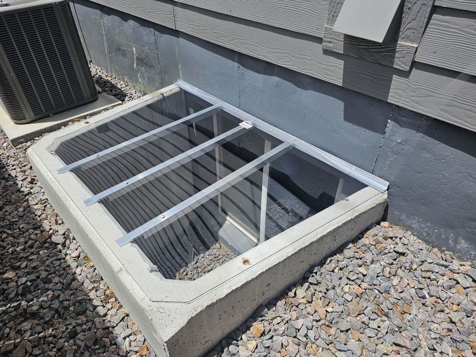 Custom clear polycarbonate window well cover with clip system installed on concrete window well 75x45 in Laporte Colorado