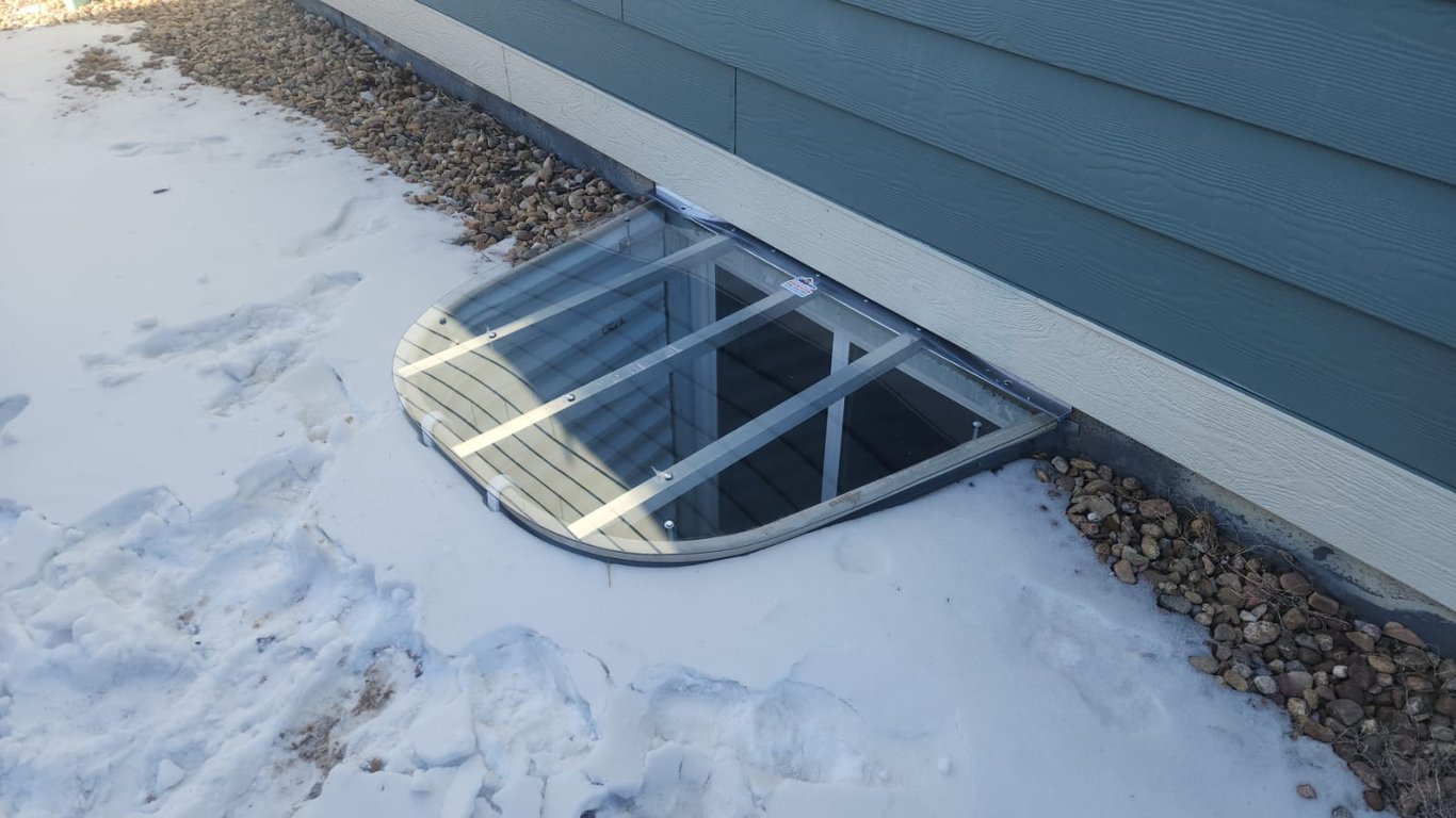 Sloped polycarbonate window well cover with snow around well installed in Forest Park Illinois