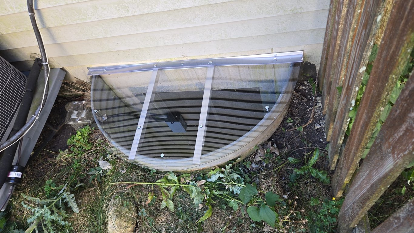 Clear polycarbonate window well cover installed near wooden fence in Harvey Illinois