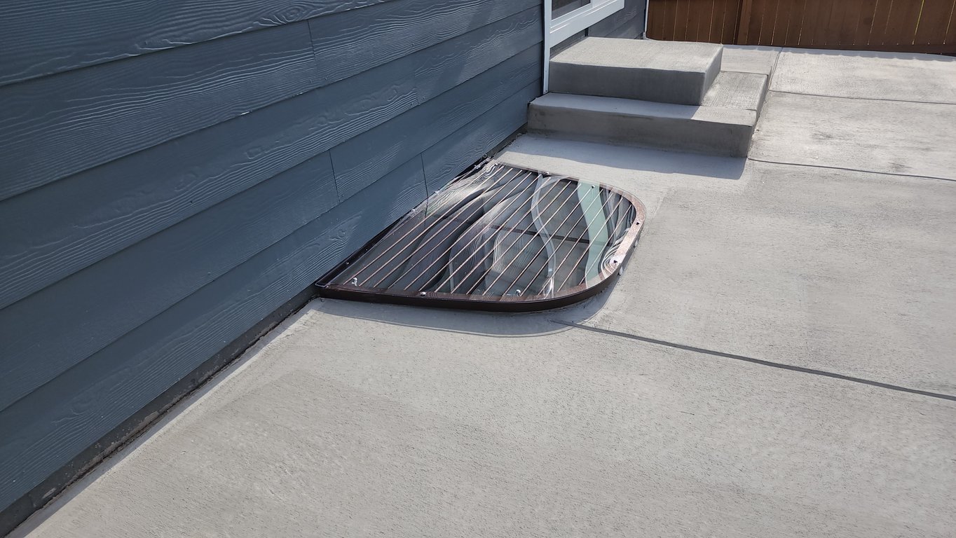 Overlay polycarbonate window well cover installed over an existing metal grate in Caledonia Wisconsin