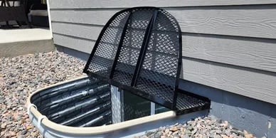 57x38 powder coated metal window well grate with escape hatch installed in Security Colorado
