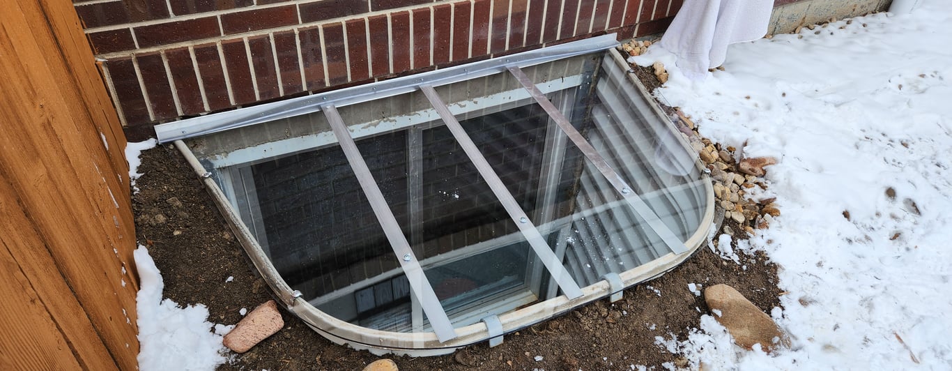 Window well cover installed on a snowy day with clips and a ladder in Downers Grove Illinois