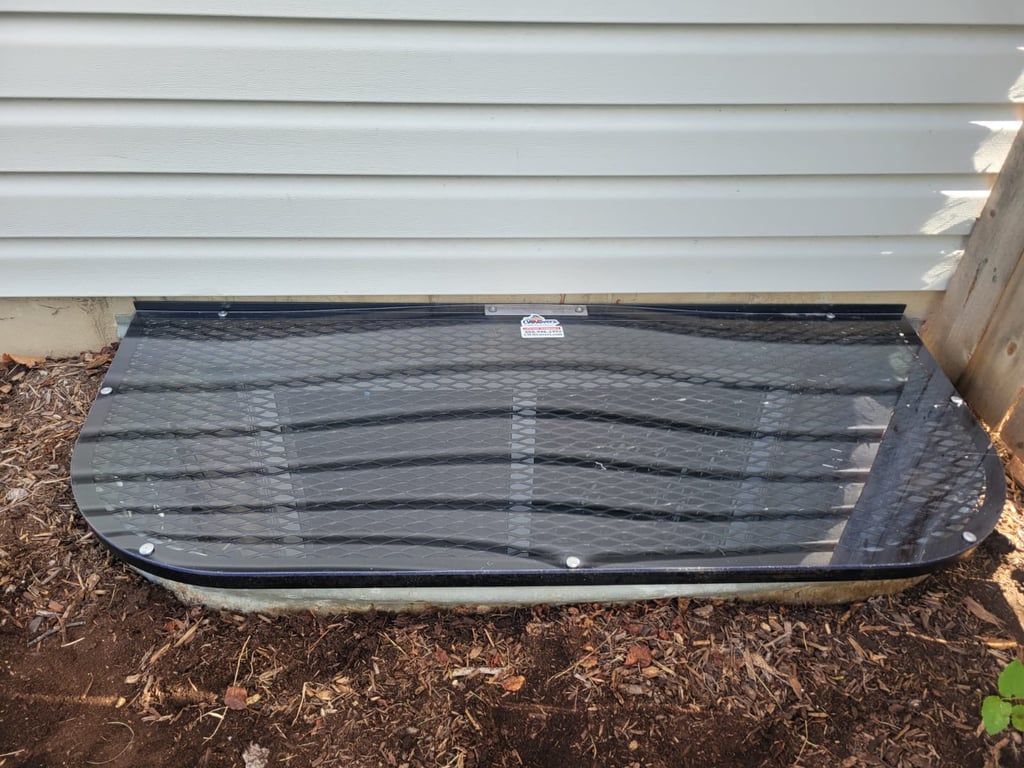 Overlay clear polycarbonate window well cover installed over existing metal grate in Federal Heights Colorado