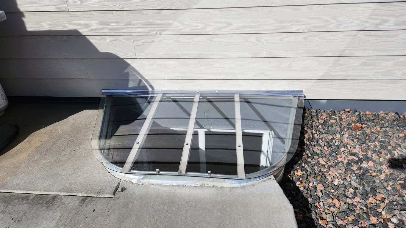 Clear polycarbonate window well cover with clips installed in Arvada Colorado