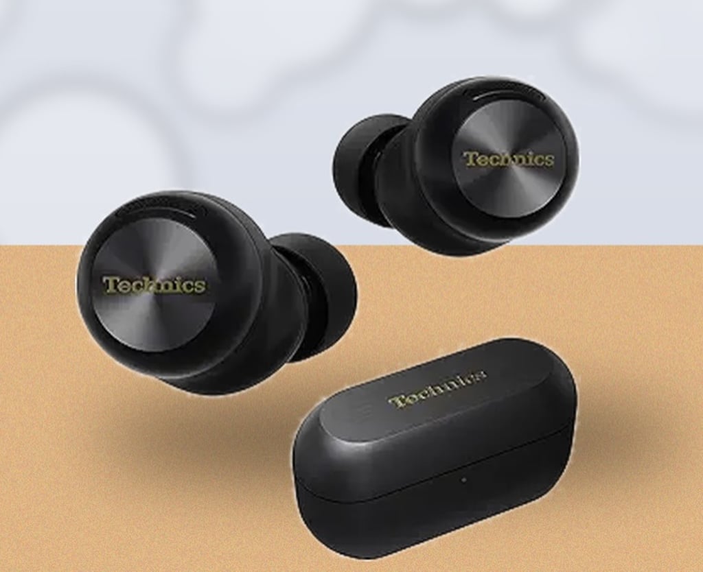 Technics EAH-AZ100 true wireless earbuds and charging case placed on a warm wooden desk with soft, natural office bokeh in the background.