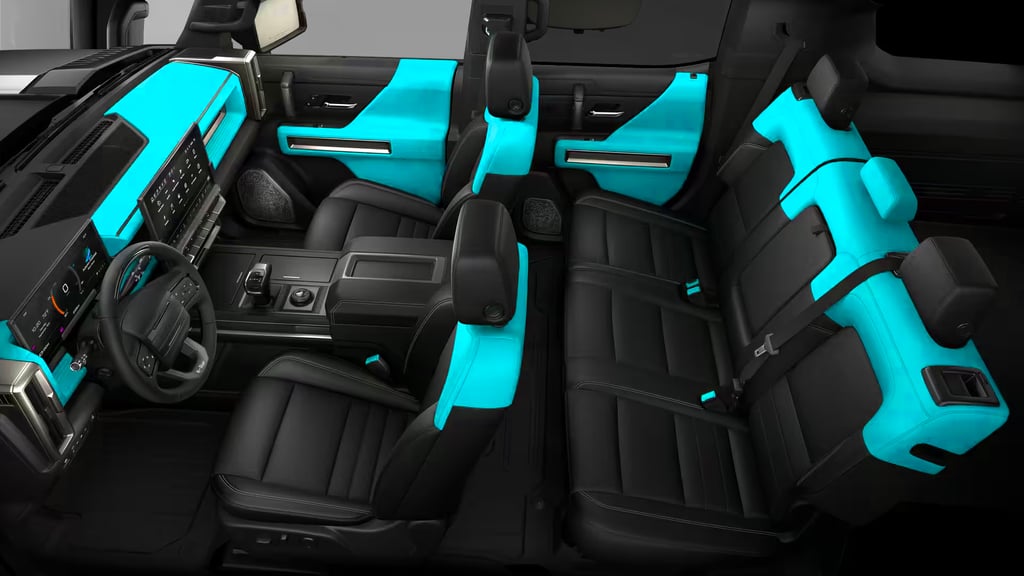 GMC HUMMER EV SUV 3X interior view showing a spacious cabin with black leather seats and bright teal accent panels across the dashboard, doors, and rear seating area, highlighting the modern infotainment screen and premium interior design.