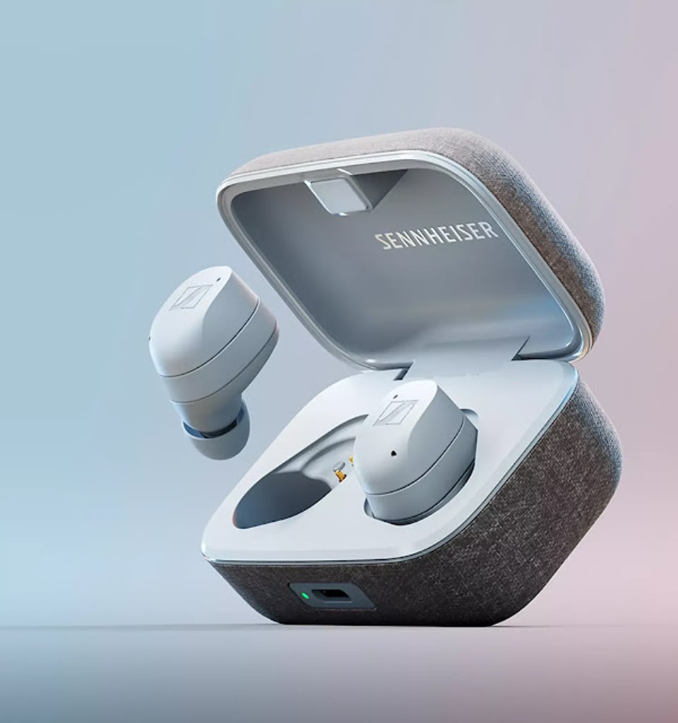 Sennheiser Momentum True Wireless 3 earbuds in an open fabric-covered charging case, highlighting the premium design, compact form factor, and wireless earbuds floating beside the case.