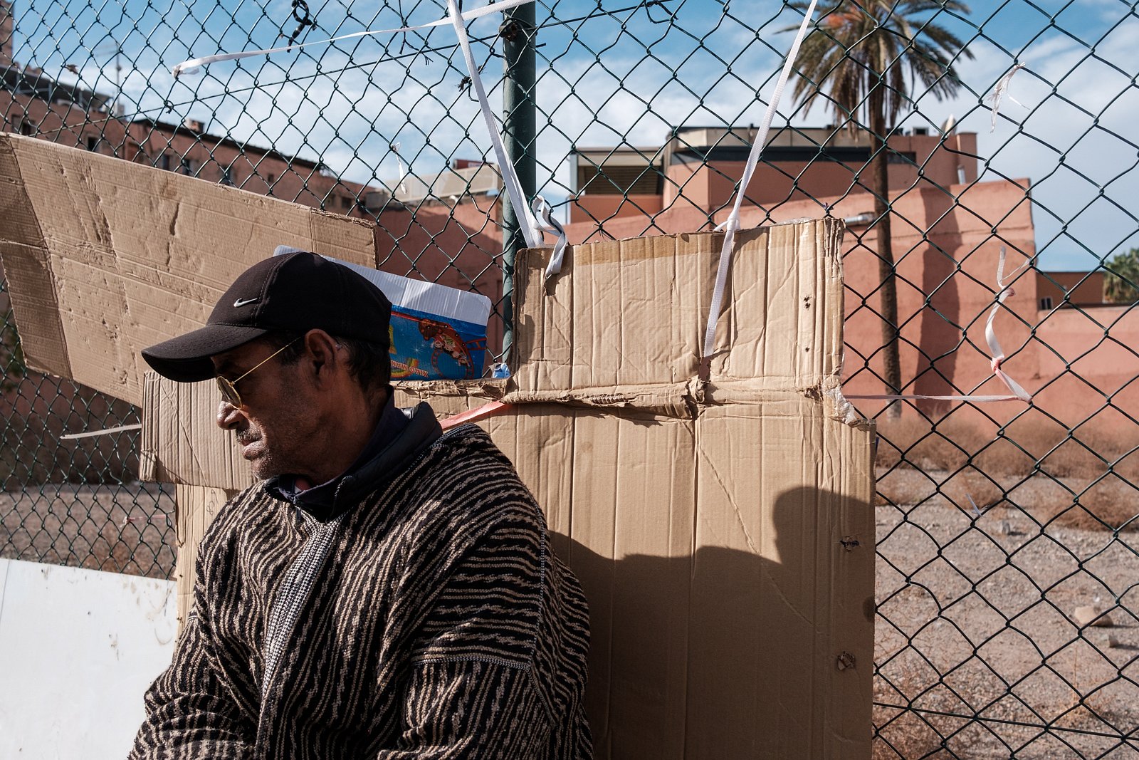 Man sitting against fencing