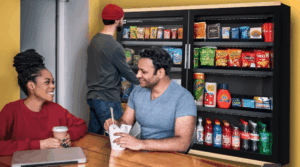 Employees enjoying snacks and drinks from a smart cooler vending machine in a modern breakroom.