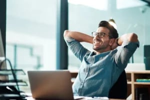 Smiling office worker relaxing at desk after completing tasks successfully