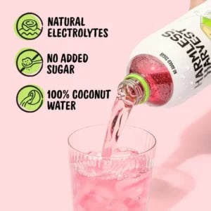 Bottle of Harmless Harvest coconut water being poured into a glass with product benefits highlighted