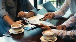 Coworkers discussing documents over coffee at a café-style workspace