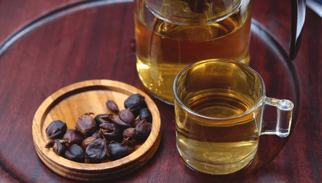 cascara tea dari biji kopi dengan gelas berisi teh yang sudah diseduh dan teko kaca di sebelahnya