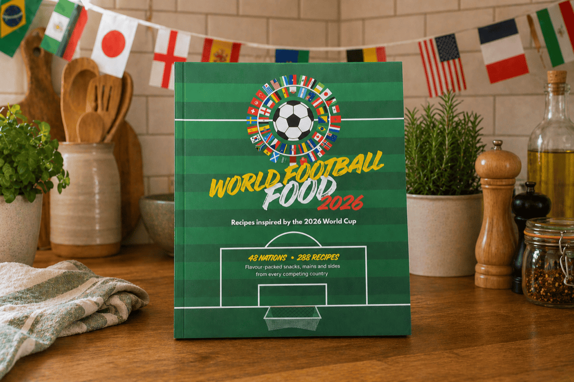 World Football Food 2026 cookbook on a kitchen counter with international flag bunting in the background.